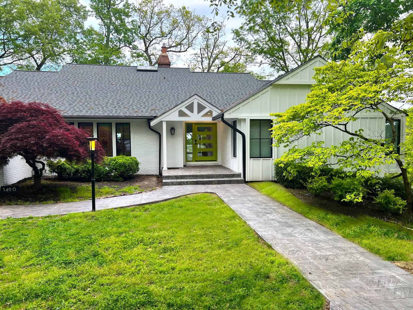 A remodeled house with a pathway leading to a newly landscaped lawn.