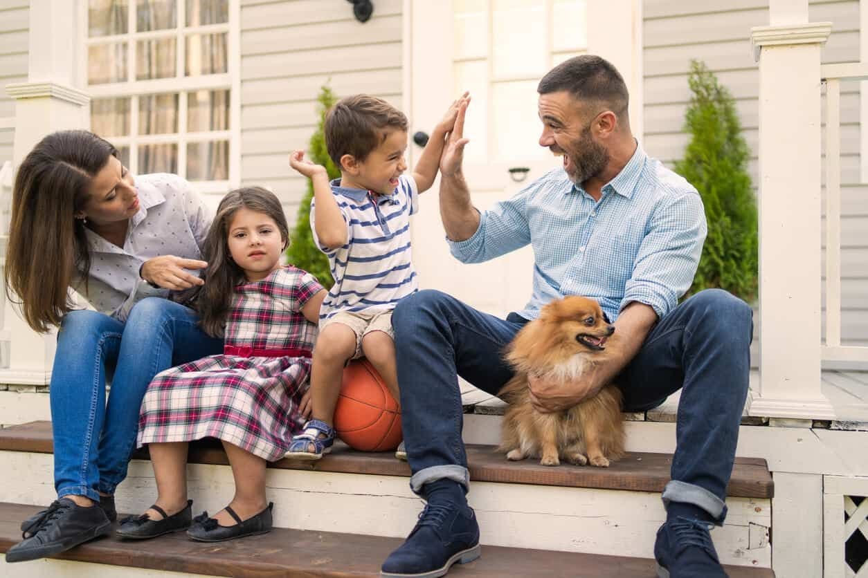 a family sits on the steps of their home.