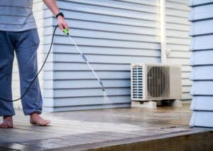 Man cleaning wooden deck with hand-held pressure sprayer