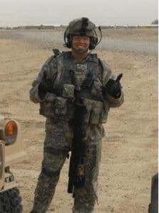 a man in camouflage standing next to a vehicle.