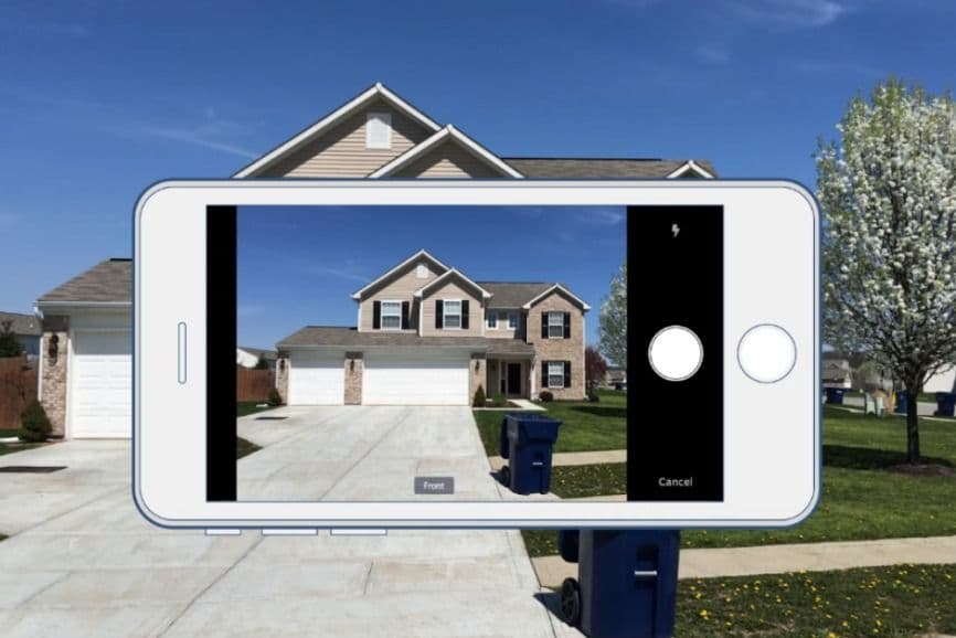 Smartphone capturing beige two-story house with double garage