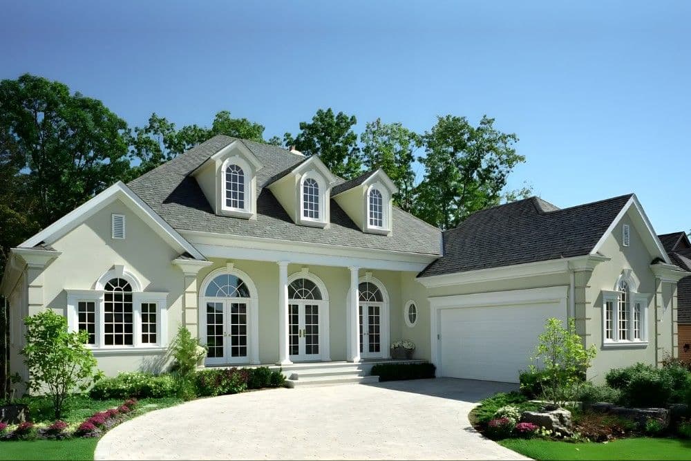 White stucco home with arched windows, dormers, and two-car garage