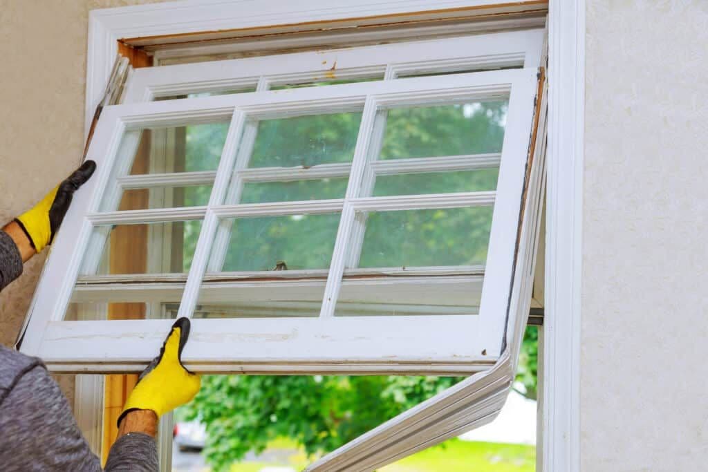 A man is replacing a double hung window in a house.